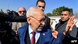 Le chef du mouvement islamiste tunisien Ennahdha Rached Ghannouchi accueille des partisans à son arrivée dans un commissariat de Tunis, le 21 février 2023,