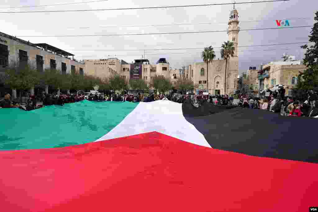 Una enorme bandera palestina fue desplegada en la plaza central de la ciudad de Belén durante una jornada navideña sin festejos, que incluyó la presentación de un pesebre con un niño Jesús entre escombros y alambres de espinos y varios discursos de solidaridad con el pueblo de Gaza.