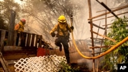 Firefighter Christian Moorhouse jumps over a fence while battling the Park Fire in the Cohasset community of Butte County, California, on July 25, 2024.