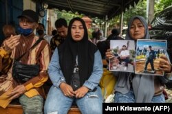 Rink Hanifah (kanan) menunjukkan foto mendiang putranya Agus Riansyah, salah satu dari 135 orang yang tewas dalam bencana Kanjuruhan 1 Oktober 2022, saat menghadiri persidangan di Pengadilan Surabaya, 16 Januari 2023. (Foto: AFP/Juni Kriswanto)