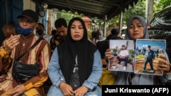 Rini Hanifah (kanan) memegang foto mendiang putranya Agus Riansyah, salah satu dari 135 korban tewas dalam tragedi stadion sepak bola Kanjuruhan 1 Oktober 2022, saat hadiri persidangan di Gedung Pengadilan Surabaya, 16 Januari 2023.