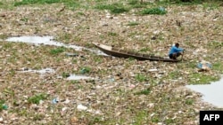 Seorang pria mengumpulkan plastik daur ulang di sungai Citarum yang tercemar di Bandung, Jawa Barat, 27 Desember 2022. (TIMUR MATAHARI/AFP)