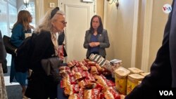 El público asistente junto a las donaciones de productos comestibles y yerba mate para residentes argentinos en Nueva York, en la sede del Consulado de Argentina en la ciudad, el 25 de mayo de 2023. [Foto: Ronen Suarc, VOA]