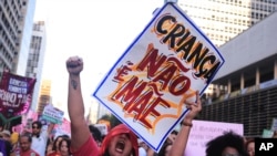An abortion rights activist holds a sign with a message that reads in Portuguese, 'A child is not a mother' during a march against an anti-abortion congressional bill in Sao Paulo, June 15, 2024.
