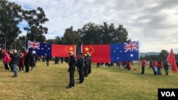 在澳大利亚国会大厦外的草坪上，欢迎中国总理李强到访的人群展示中澳两国国旗。（2024年6月17日）