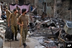 Petugas polisi melihat puing-puing rumah yang dirusak massa Muslim yang marah di kawasan Kristen di Jaranwala di distrik Faisalabad, Pakistan, Kamis, 17 Agustus 2023. (Foto: AP)