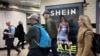 资料照：英国伦敦市民走过地铁走道旁挂着的便宜服装快时尚品牌Shein的广告牌。（2024年3月8日）