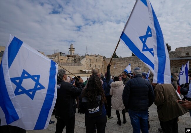 Israelis wave national flags during protest against plans by Prime Minister Benjamin Netanyahu's new government to overhaul the judicial system, at the Western Wall plaza in the Old City of Jerusalem, Monday, Feb. 13, 2023. (AP Photo/Ohad Zwigenberg)