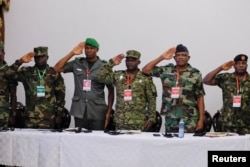 Military personnel gesture as the ECOWAS anthem is played during a meeting of the Committee of Chiefs of Defense staff on the deployment of the ECOWAS standby force in the Republic of Niger, in Accra, Ghana, Aug. 17, 2023.
