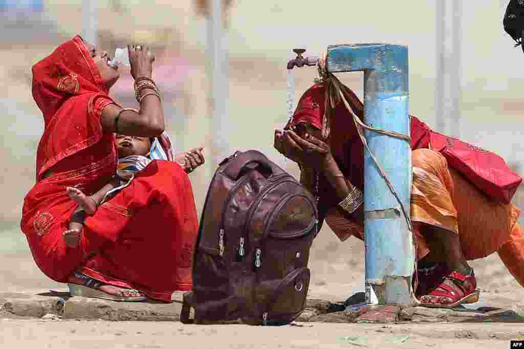 Women quench their thirst with tap water on a hot summer afternoon during a heat wave in Prayagraj, India. India's heat wave is the longest ever to hit the country.