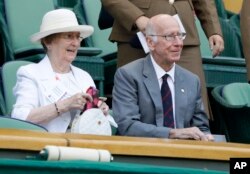 Bobby Charlton dan istrinya, Lady Norma, menyaksikan laga tenis di Kejuaraan Tenis Wimbledon di London, 7 Juli 2018. (Foto: Kirsty Wigglesworth/AP Photo)