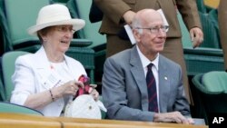 FILE - Former England soccer player Bobby Charlton and his wife sit in the Royal Box on Centre Court on the sixth day of the Wimbledon Tennis Championships in London, July 7, 2018.
