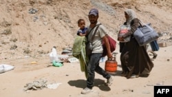 Palestinians carry their belongings as they flee a makeshift camp for displaced people in Khan Younis in the southern Gaza Strip after Israeli tanks took position on a hill overlooking the area, August 18, 2024.