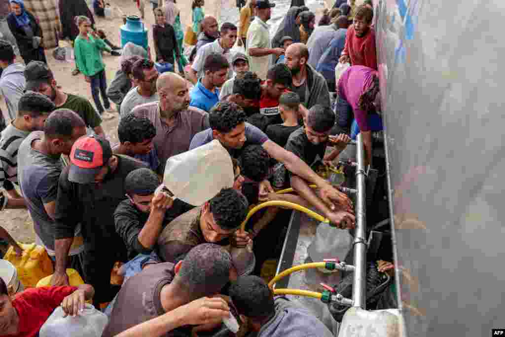 People gather with jerrycans and other containers to collect water from a tanker cistern in Deir el-Balah in the central Gaza Strip amid the ongoing conflict in the Palestinian territory between Israel and the militant group Hamas.