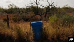 FILE - A water station for immigrants containing sealed jugs of fresh water sits along a fence line near a roadway in rural Jim Hogg County, Texas, July 25, 2023.