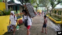 Evacuees carry their belongings as they arrive at a temporary relocation site at a school in Daraga town, Legaspi, Albay province, northeastern Philippines, June 10, 2023. 