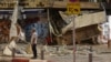 A man stands in front of a damaged shop in Tel Aviv, after it was hit by a rocket fired by Palestinian militants from the Gaza Strip, Oct. 7, 2023.