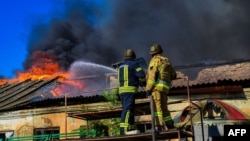 This handout picture taken and released by Ukraine's Emergency Service on Sept. 19, 2023, shows firefighters extinguishing a fire in a warehouse after Russian shelling in Kherson, Ukraine. Russian troops again pounded the Kherson region on Sunday.