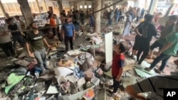 In this image made from a video, people inspect the dome at a school after being hit by an Israeli airstrike in Gaza City, Aug. 10, 2024.