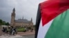 Un manifestante solitario ondea la bandera palestina frente al Palacio de la Paz, en la parte trasera, que alberga la Corte Internacional de Justicia, o Corte Mundial, en La Haya, Países Bajos, el viernes 24 de mayo de 2024.