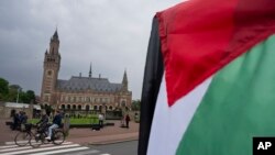 Un manifestante solitario ondea la bandera palestina frente al Palacio de la Paz, en la parte trasera, que alberga la Corte Internacional de Justicia, o Corte Mundial, en La Haya, Países Bajos, el viernes 24 de mayo de 2024.