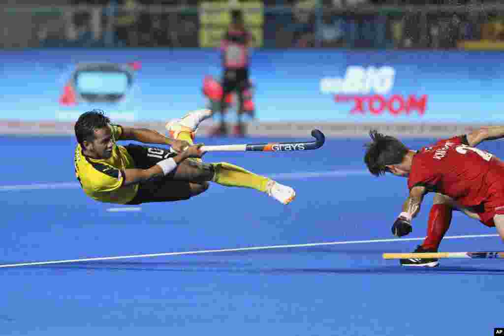 Malaysia&#39;s Faizal Saari is in the air as he hits the ball past Korea&#39;s Hyeongjin Kim during the first semifinal men&#39;s Asian Champions Trophy hockey match between Malaysia and Korea in Chennai, India.