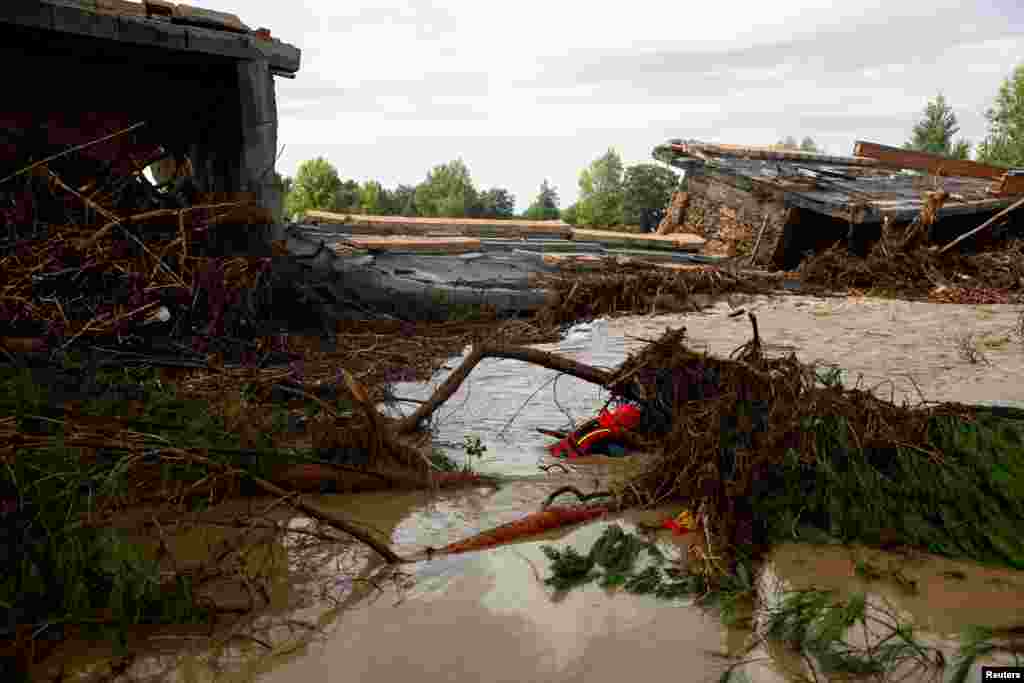 A member of the Spanish Civil Guard search and rescue team looks for a missing person by a bridge that partially collapsed, following heavy rain in Aldea del Fresno, Spain.
