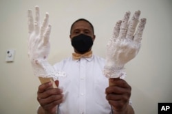 DeAndre Muhammad holds up plastic casts of his hands in a studio at the Gibbes Museum of Art in Charleston, S.C., on Thursday, Feb. 16, 2023. (AP Photo/Allen G. Breed)