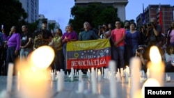 A person holds Venezuela's national flag with the writing "Venezuela, free and democratic" during a vigil in tribute to citizens who were detained following disputed election results, in Caracas, Venezuela, Aug. 8, 2024.