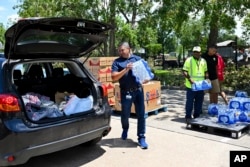 FILE - Volunteers hand out water at a distribution station in Houston, July 10, 2024.