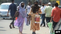 করোনাভাইরাস ছড়িয়ে পড়ার আশঙ্কার মধ্যে ফেসমাস্ক পরে ঢাকার একটি রাস্তা দিয়ে হাঁটছেন লোকজন। ৯ মার্চ, ২০২০। (ফাইল ছবি) 