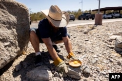 Seorang pengunjung mencoba menggoreng telur di atas batu panas di bawah sinar matahari di Pusat Pengunjung di Taman Nasional Death Valley, dekat Furnace Creek, selama gelombang panas melanda California Selatan pada 7 Juli 2024. (Foto: AFP)