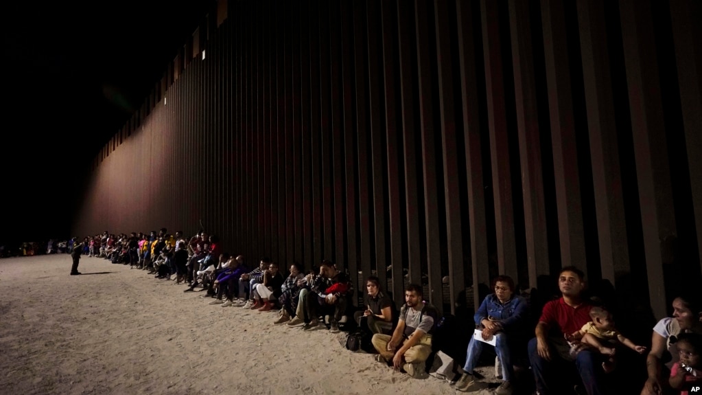 资料照片：越过墨西哥边境的移民在美国边境墙边等待进入美国。(2022年8月23日）(photo:VOA)