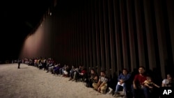 資料照片：越過墨西哥邊境的移民在美國邊境牆邊等待進入美國。(2022年8月23日）