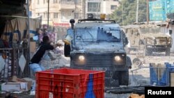 A Palestinian throws a paint bucket at an Israeli military vehicle during a raid in Nablus in the Israeli-occupied West bank.