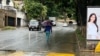 Una mujer camina en una calle de Caracas resguardada de la lluvia bajo un paraguas, el martes 30 de mayo de 2023.