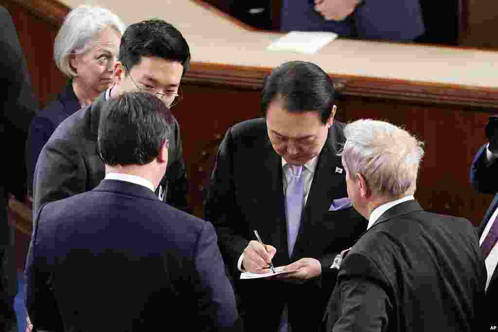 윤석열 한국 대통령이 27일 미 의회 상하원 합동회의 연설을 마친 후 의원들의 요청에 사인을 하고 있다.