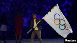 Aktor Tom Crusie membawa bendera olimpiade dalam upacara penutupan Olimpiade Paris yang digelar di Stade de France, Saint-Denis, pada 11 Agustus 2024. (Foto: Reuters/Albert Gea)