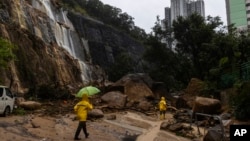 Workers walk through a landslide following heavy rainstorms in Hong Kong, Sept. 8, 2023.