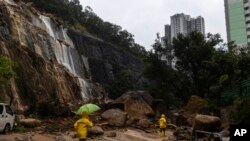 2023 年 9 月 8 日，香港暴雨過後工人們走過山體滑坡現場。