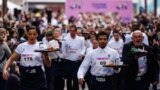 Waiters and waitresses in work outfits compete in a traditionnal "Course des cafes" (the cafes' race), in front of the City Hall in central Paris, March 24, 2024. 