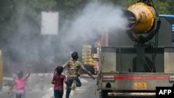 Children run behind a truck spraying water along a street on a hot summer day in New Delhi on May 28, 2024.