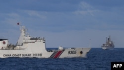 A Chinese Coast Guard ship sails near a Philippine vessel, right, that was part of a convoy of civilian boats in the disputed South China Sea on Dec. 10, 2023.