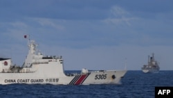 A Chinese Coast Guard ship sails near a Philippine vessel, right, that was part of a convoy of civilian boats in the disputed South China Sea on Dec. 10, 2023.