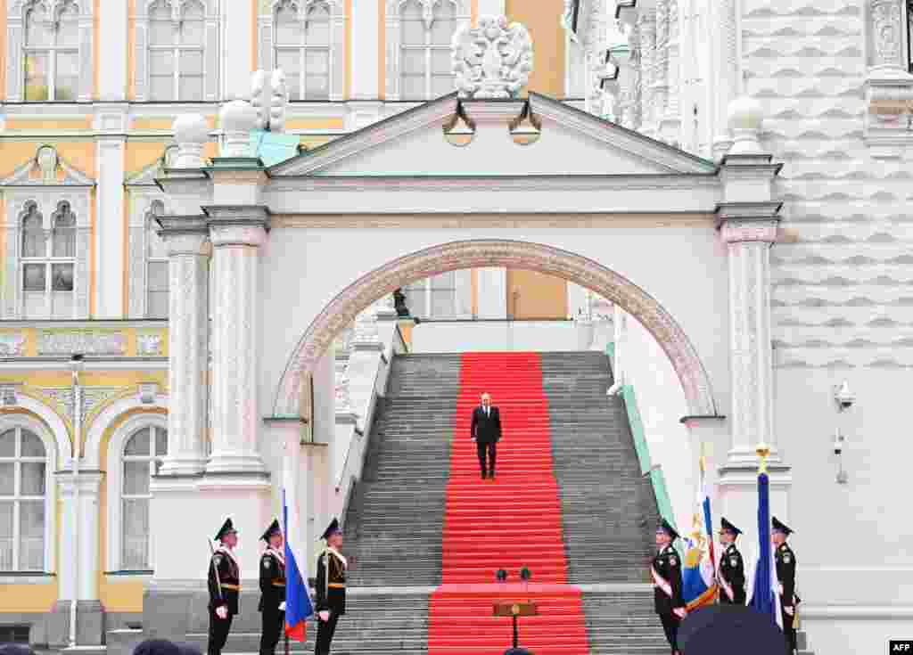 Presiden Rusia Vladimir Putin berjalan menuruni tangga untuk berpidato kepada pasukan yang berkumpul di Lapangan Sobornaya dari serambi Istana Sisi di halaman Kremlin di Moskow.