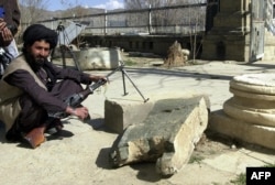 FILE - A soldier of Taliban militia sits beside a broken piece of lion statue outside the Afghan's capital Kabul Museum, March 22, 2001.