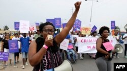 FILE - Hundreds of Angolans hold placards and shout slogans as they march to protest against a draft law that would criminalize all abortion on March 18, 2017 in Luanda, Angola. 