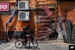 A boy rides a bicycle past the damage after a bomb explosion in Tel Aviv, Israel, Aug. 19, 2024.