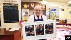 Butcher Anthony Heffernan shows pictures of President Joe Biden with him taken in 2016 when Biden was vice president, in his shop, April 4, 2023, in Ballina, Ireland.