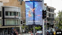 A banner depicting the mythical Persian hero Arash the archer firing a missile from his bow, with text in Persian reading 'I will not abandon my homeland', is displayed along a street in central Tehran on April 15, 2024. 